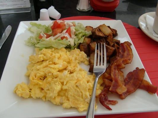 scrambled eggs, bacon, potatoes and salad