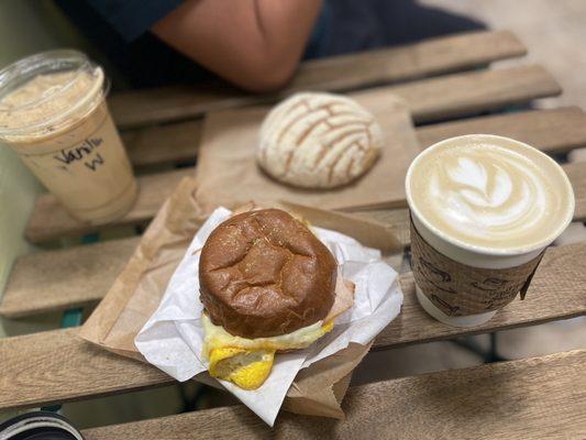 Iced vanilla latte, cafe de olla latte, concha and breakfast sandwich