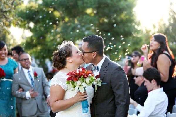 Walking back down the aisle after tying the knot - love all the bubbles in the background!