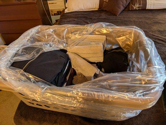 The folded laundry in a plastic bag in our provided laundry basket.