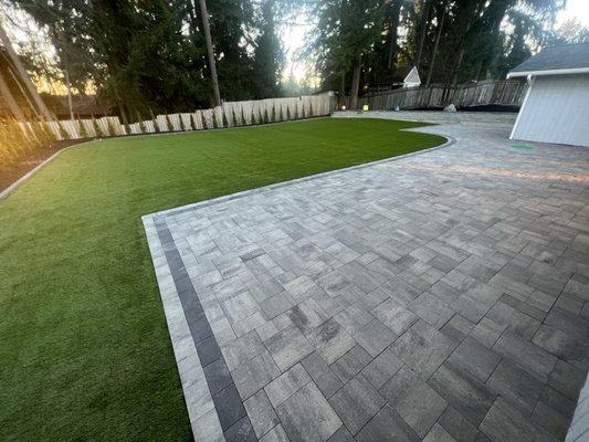 Paver patio, artificial grass, planter with raised edge and retaining wall.