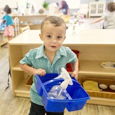 One of our toddler students taking a practical life activity off the shelf.