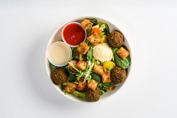 falafel & greens salad: baby kale, romaine,falafel, scallions, tomatoes, cucumbers, hummus, pita croutons with lemon tahini and hot sauce