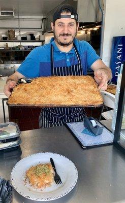 Owner Nars Muhammad (perhaps owner) holding freshly baked dessert.