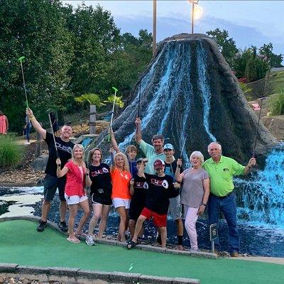 Family posing in front of volcano at Volcano Falls Mini Golf course at Funtrackers Family Fun Park in Hot Springs, AR