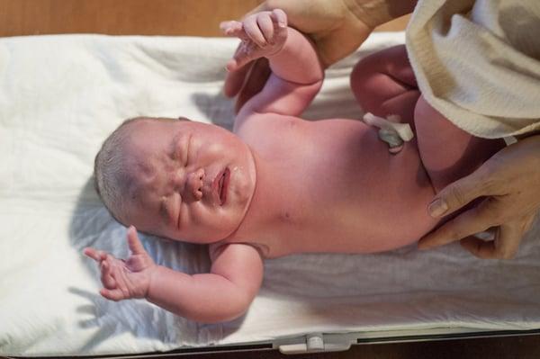 Getting weighed during a newborn exam.