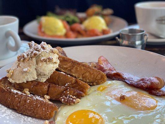 French toast with eggs and bacon. Salmon pastrami  Benedict in the background.