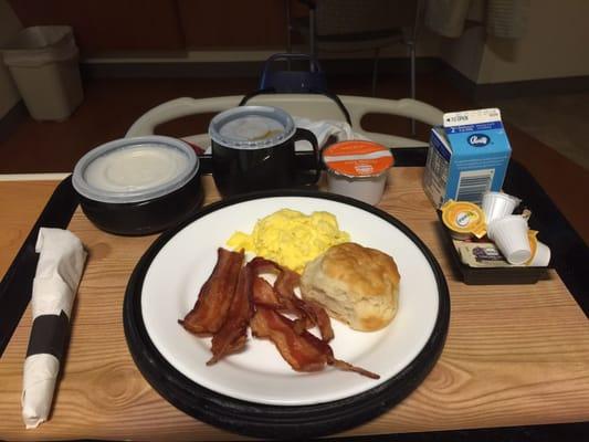 Breakfast of champions! Scrambled eggs, bacon, biscuit, grits, milk, orange juice, coffee, and of course any condiment you need!