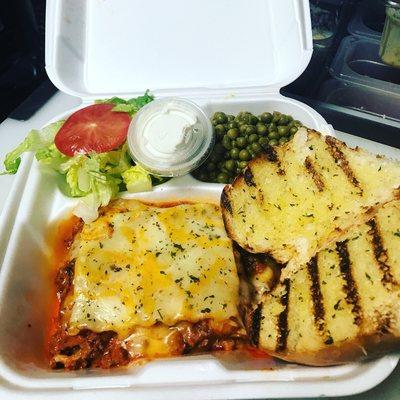 Klutch Lasagna plate with green peas, salad and garlic bread