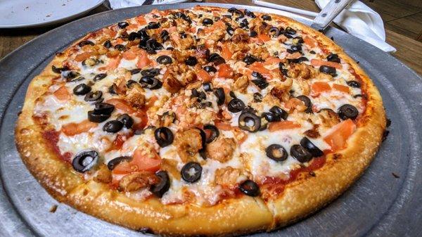 Large pizza with tomatoes, olives, fresh garlic and chicken.