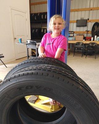 Ellie is little standing next to these huge tires for the tow truck!