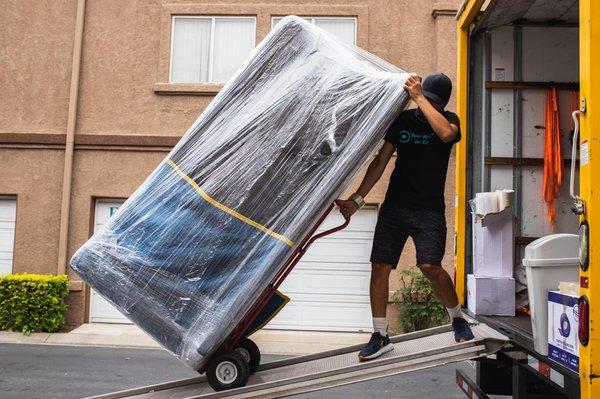 Well wrapped, safely carried - just one mover is taking care of one big couch.