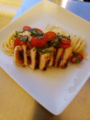 Grilled chicken and pasta topped with fresh cherry tomatoes, herbs and a white wine lemon sauce