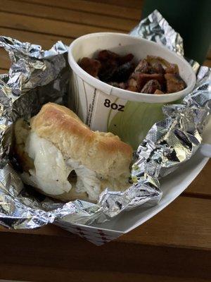 Breakfast Biscuit (half eaten) and side of breakfast potatoes and onions.