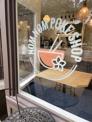 Nom Nom Poké Shop logo on large window which brings in natural light