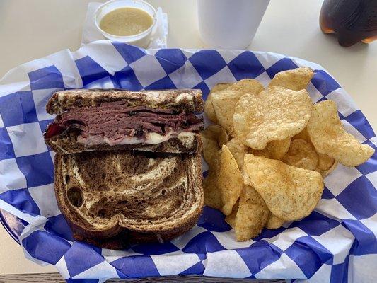 Pastrami sandwich with smoked provolone on toasted marble rye bread with Mrs. Vickys jalapeño kettle chips.