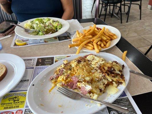 Irish omelette with corned beef , Cheddar cheese and potatoes. Well done fries with a Greek salad. Rye toast in the left corner.