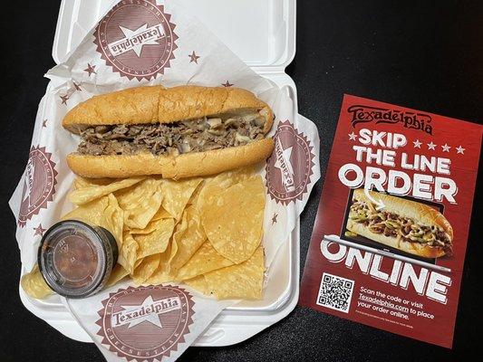 Small size beef cheesesteak sandwich, with chips and hot sauce.