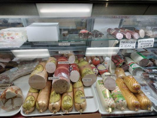 Below: Head cheese, bologna, and veal bologna.  Above: Hard salamis from Moldova and Estonia; goose liver (?) and a cake, sold by the pound.