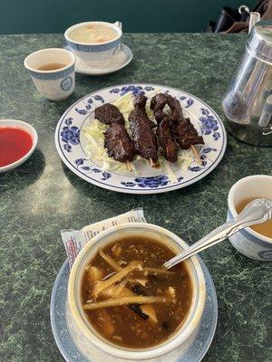 Sweet and sour soup, beef skewers, egg drop soup, and tea