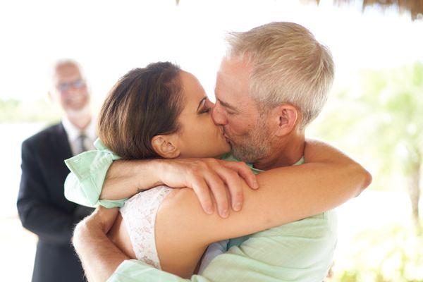 Summer Bride and groom kissing at ceremony.