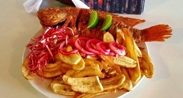 Tilapia Roja, servida con tajadas de platano verde y encurtidos