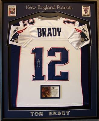 A jersey framed with 2 trading cards and the official certificate of authenticity.