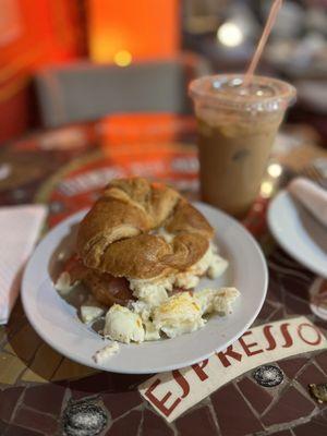 Egg white bacon egg and cheese on a croissant and dulce de leche iced latte with almond milk, large