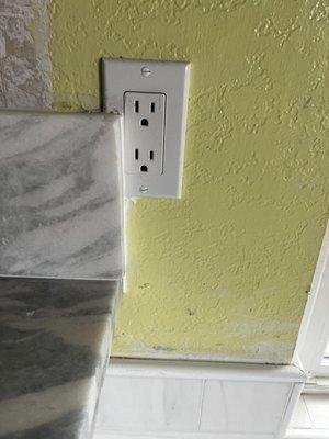 Install of backsplash over electrical outlet. Clearly they did not care how the final product looked.