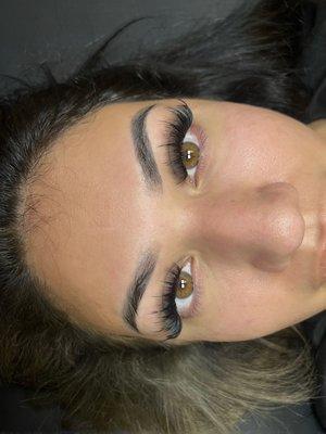 Wispy strip lash look with full volume eyelash extensions. Ombré powder brows healed 1 year.