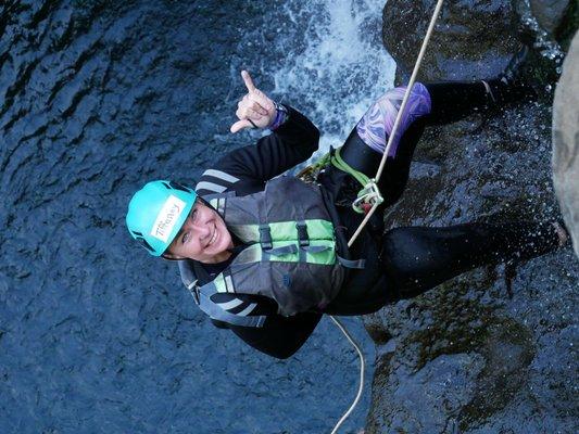 Shaka while waterfall rappelling