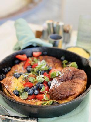 Mixed Berry Dutch Baby Pancake Cake, served on a hot skillet with side of lemon custard and sirup