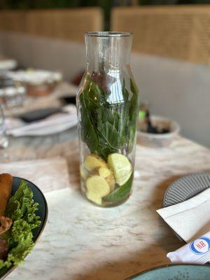 Water infused with basil leaves, sliced ginger root and cut limes.