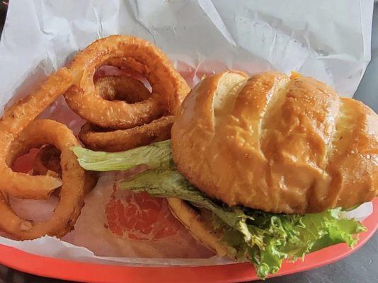 Cheeseburger with added lettuce, tomato and onion and onion rings.