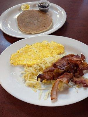 Scrambled eggs, bacon, pancake, hash browns