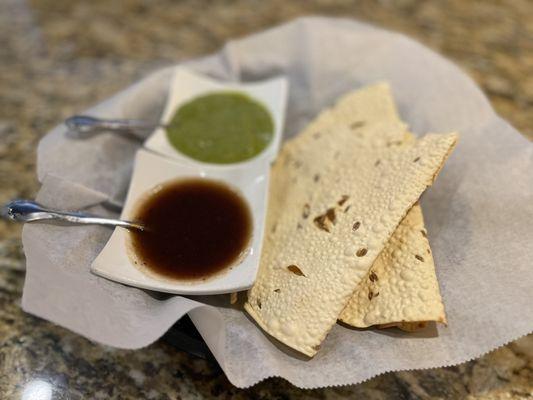 Complimentary, crispy bread with red sauce (sweet) and green sauce (spicy).