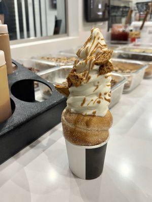 Vanilla soft serve with biscoff syrup, drizzle and crumbles in a cinnamon sugar cone