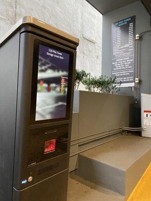 Ticket machine at entry with current parking rates and hours displayed.