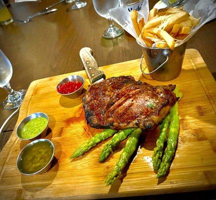 Ribeye steak served with fries and asparagus.