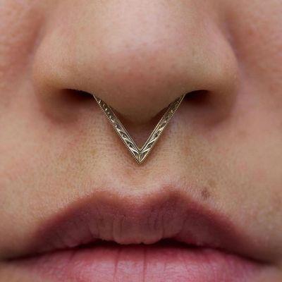 Septum piercing with the Fiat Lux engraved Apollo hinged clicker ring in yellow gold.