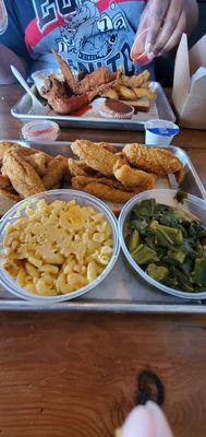 Fried perch macaroni and cheese and collard greens. The other plate has fried Chicken wings, perch, macaroni and cheese and French fries.