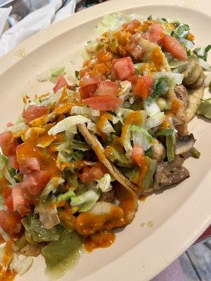 Cactus, mushroom, and pumpkin flower tacos, topped with lettuce, tomato, onion, cilantro, and salsa