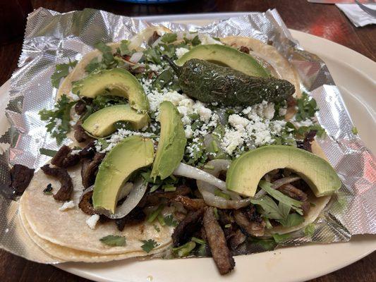 Mini beef tacos with avocado, grilled onions and jalapeño, cilantro and cotija cheese. Delicious.