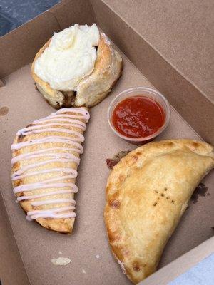 Cinnamon roll, blueberry lemon cheesecake hand pie, pizza hand pie