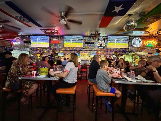 Tables and bar with baseball on the screens. there are more screens than these however.