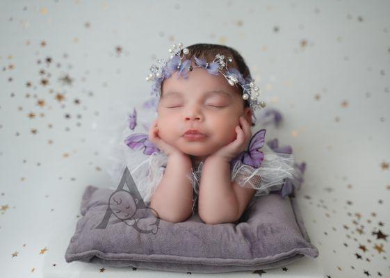 Newborn Baby Photography. Baby posed with hands on chin wearing butterfly outfit.