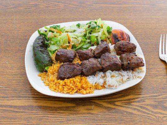 Lamb shish kebab served with rice, bulgur and mixed greens seasoned with extra virgin olive oil and vinegar