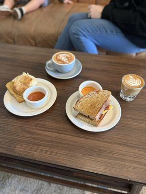 Bacon breakfast sandwich, biscuit and jam, cappuccino and cortado.