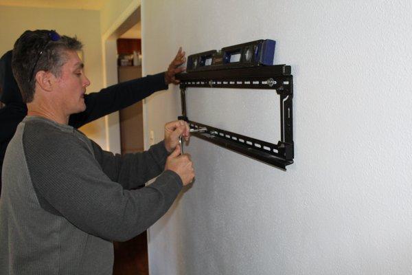 Technicians at work installing a TV mount.