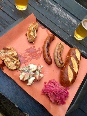 3 sausages with 3 sides (savory bread pudding, potato salad, sauerkraut) plus pretzel bread